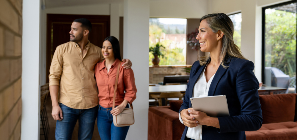Un couple visite une nouvelle maison avec un agent immobilier, symbolisant le processus d’achat de votre première maison.