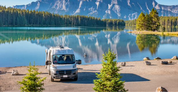 Un VR est stationné au bord d’un lac dans un parc national de l’Alberta avec les montagnes Rocheuses en arrière-plan.