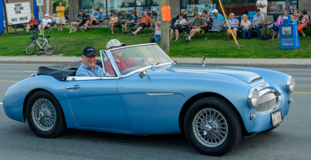 Un conducteur et un passager portant des casquettes roulent dans une Austin Healey 3000 des années 1960 un samedi soir sur le chemin Mountain lors de l'Atlantic Nationals Automotive Extravaganza de 2015.