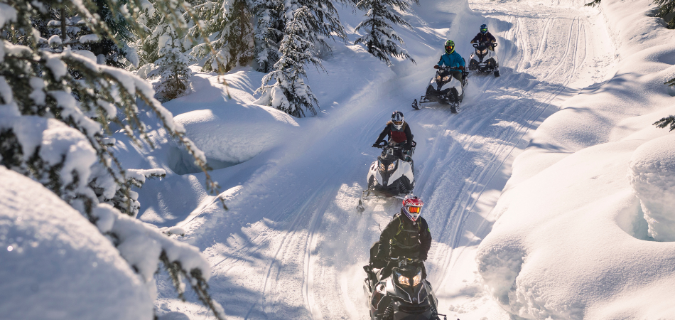 Un groupe de personnes faisant de la motoneige sur une piste en hiver.