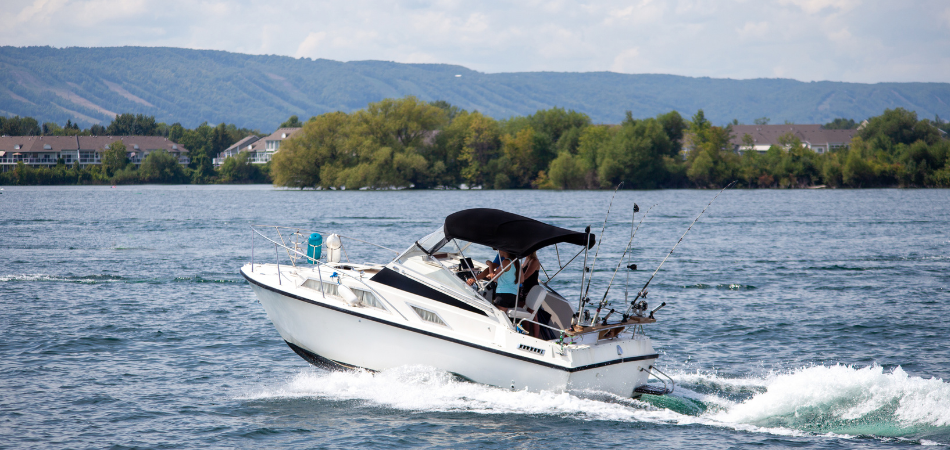 Bateau à moteur naviguant sur un lac canadien calme près d’une rive boisée.  