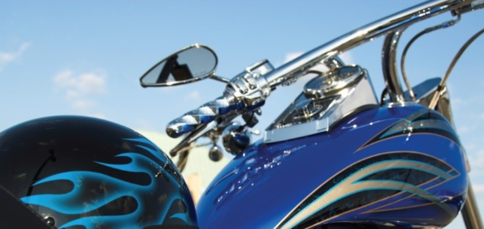 Gros plan d'une moto bleue avec des pièces chromées et des autocollants de flammes sur le réservoir et le casque.