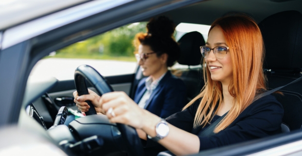 Une jeune femme rousse qui conduit un véhicule lors d’un cours de conduite avec une monitrice