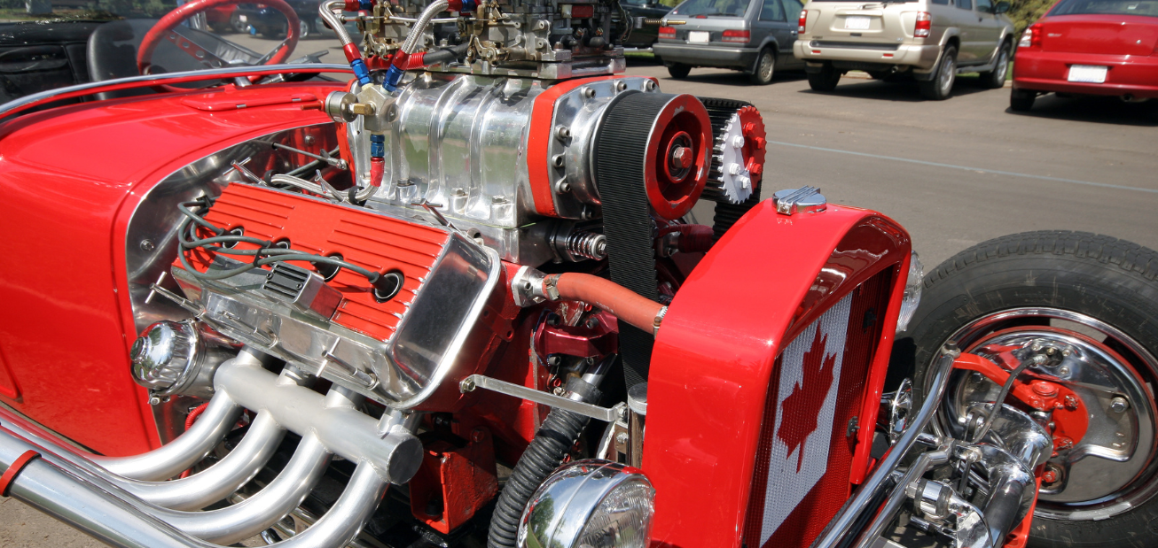 Une voiture de haute performance de couleur rouge avec des pièces automobiles de rechange et un drapeau canadien à l’avant.