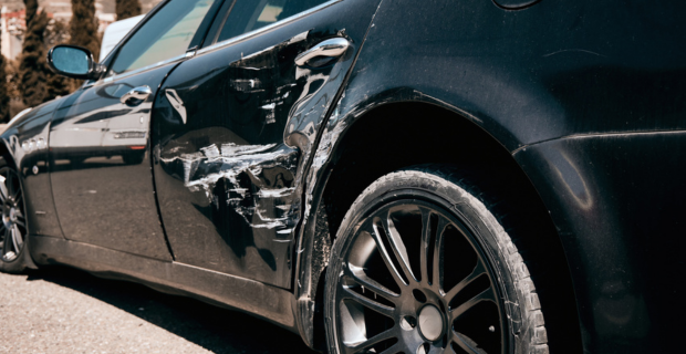 Image rapprochée d’une voiture noire avec des dommages structurels sur le côté. 