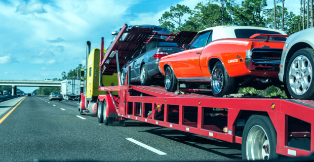 Une remorque à plateau livrant une Honda Accord, une Mercedes-Benz CLK 430 décapotable, une Ford Fusion familiale et une Mercury Cougar Eliminator décapotable des années 1960. 