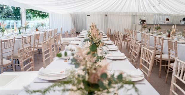 Réception de mariage sous un chapiteau blanc avec des fleurs et des décorations sur les tables.