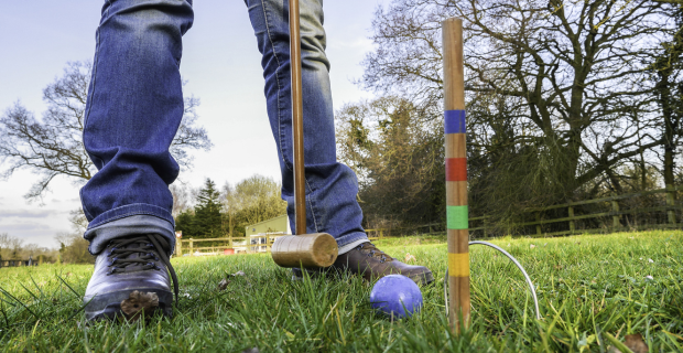 Personne debout et jouant au croquet sur l'herbe