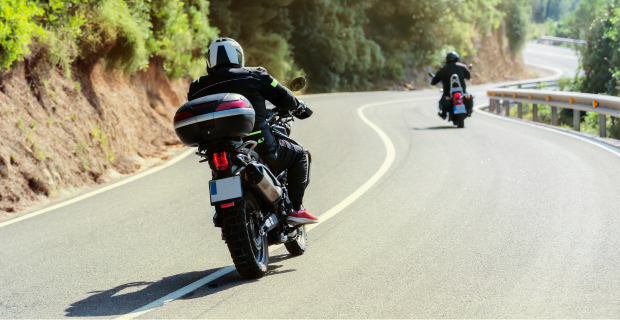 Des motards circulant sur une route sinueuse à flanc de colline. 