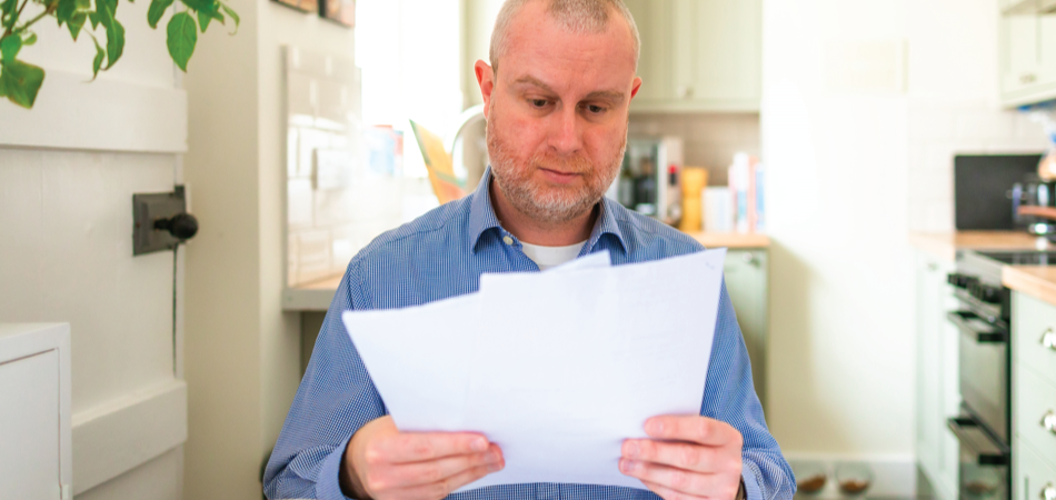 Personne en chemise bleue lisant des journaux dans une cuisine.