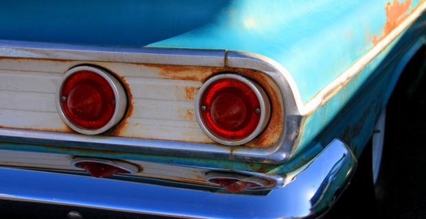 Vue arrière d'une voiture classique avec de la rouille autour des feux arrière et sur la carrosserie. 