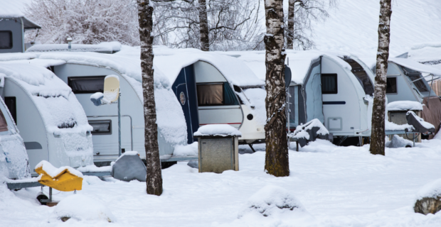 Une rangée de camping-cars couverts de neige pendant l'hiver.