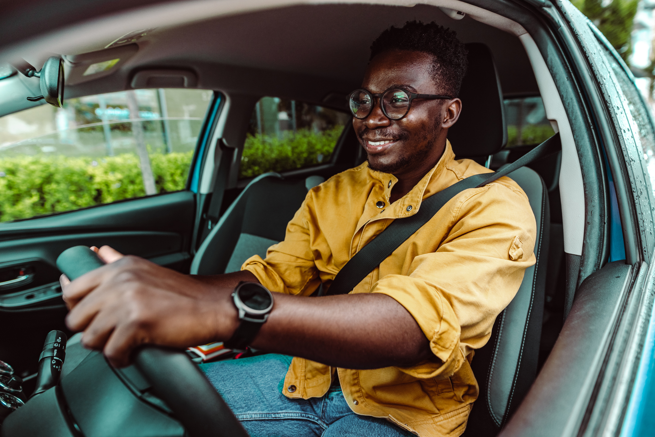 Un homme portant des lunettes est assis au volant de sa voiture