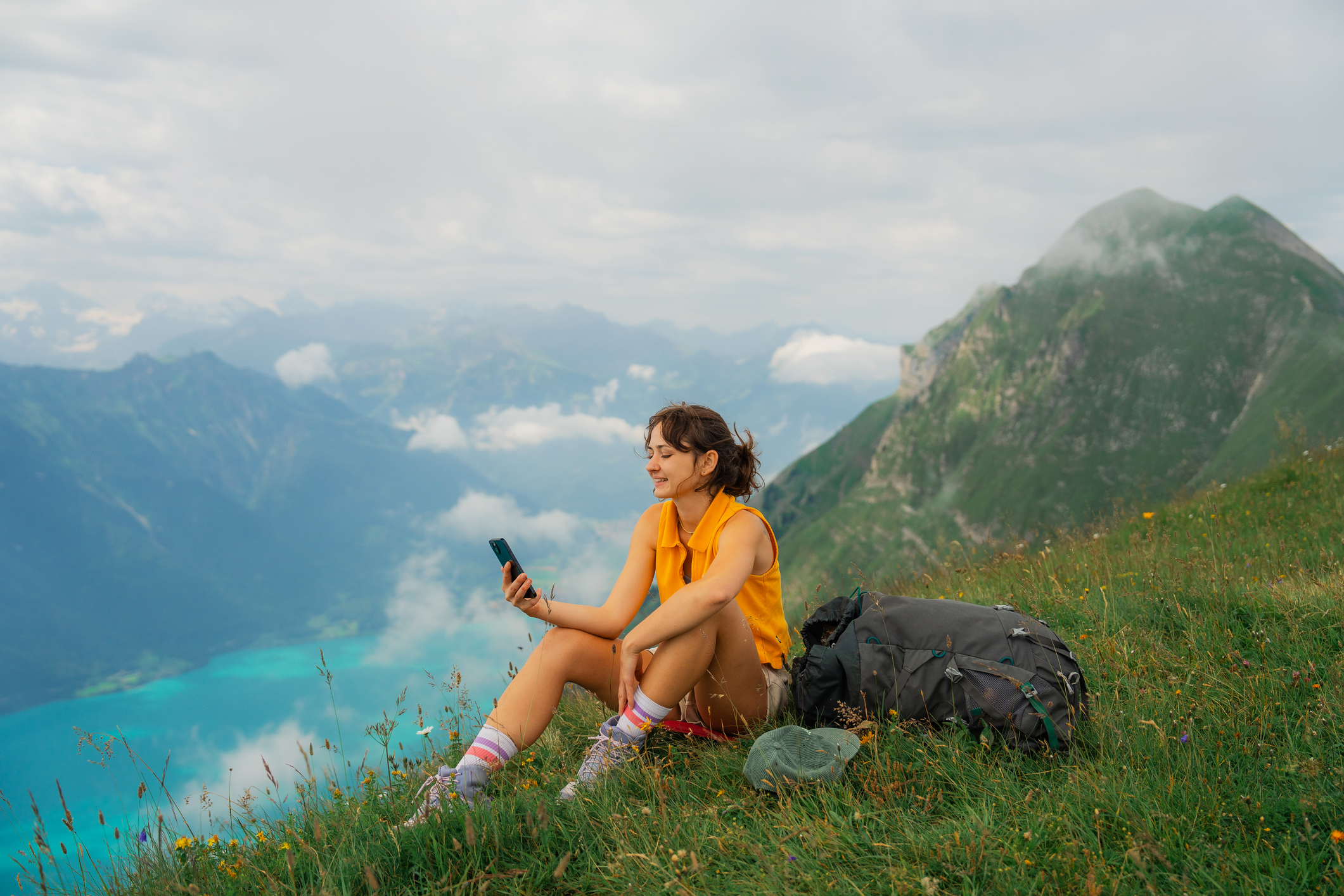Une femme assise dans les montagnes consultant son téléphone intelligent