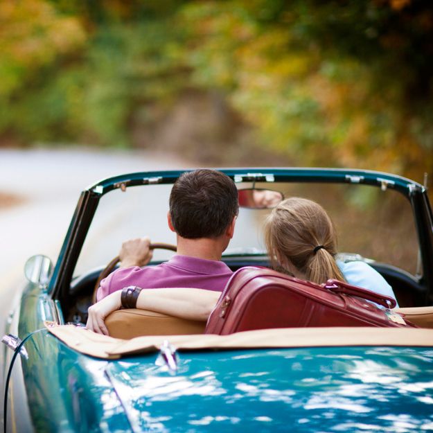 Un couple dans une voiture classique décapotable bleue pour une promenade tranquille.