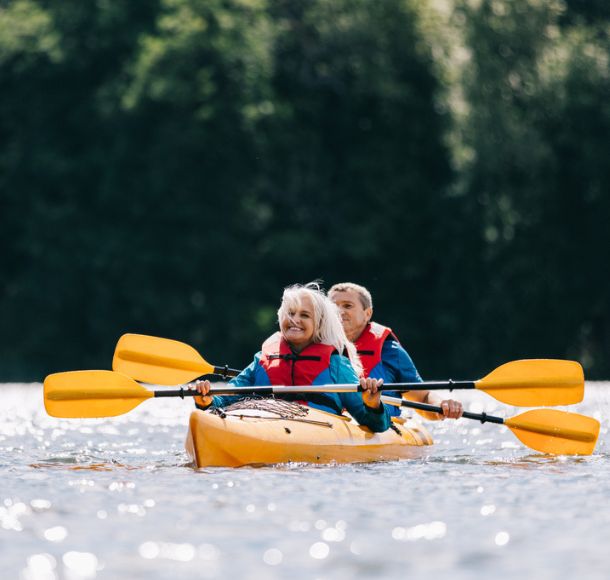 Un couple de retraités pagayant un kayak pour deux personnes lors d'une journée d'été ensoleillée en Alberta.