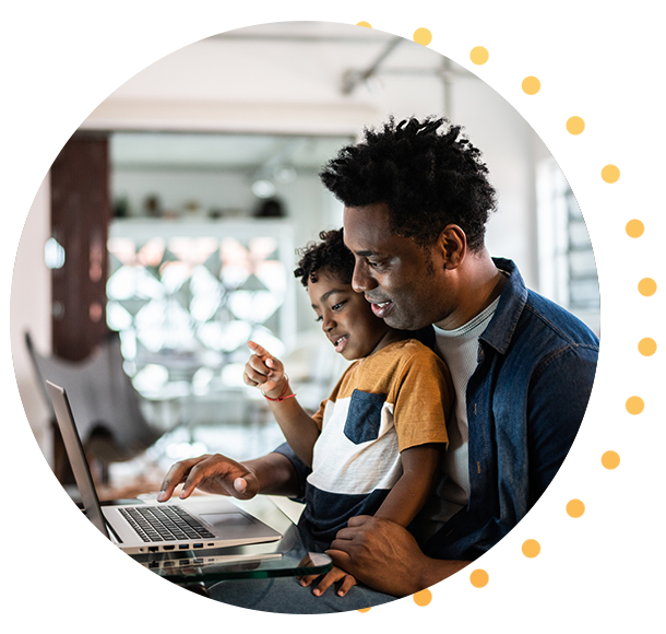 Homme utilisant un ordinateur portable avec son fils assis sur ses genoux à la maison
