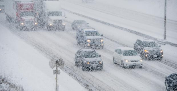 Véhicules sur la route durant une tempête hivernale.