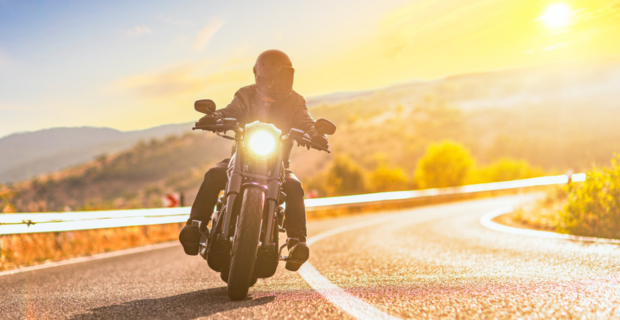 Image d’un coucher de soleil et d’un homme à moto.