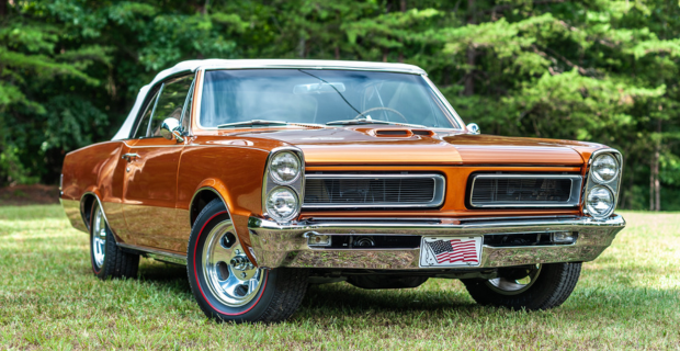 Une Pontiac GTO orange garée dans un champ.