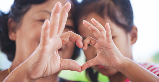 Un adulte et un enfant joignent leurs mains pour former un cœur..