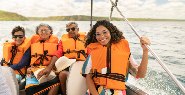 Des plaisancier.ère.s portant des gilets de sauvetage à bord d’un bateau en été, respectant les consignes de sécurité nautique.   