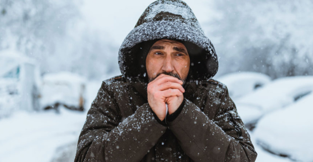 Un homme essaie de se réchauffer les mains en hiver.