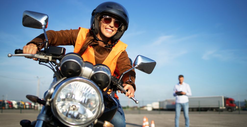 Une jeune femme conduit une moto lors d’un examen de conduite par une journée ensoleillée.