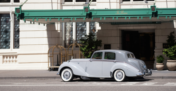 Une Rolls-Royce ancienne garée devant un hôtel