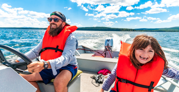 Un père et sa fille sont sur leur bateau portant des gilets de sauvetage et pratiquent la sécurité nautique.