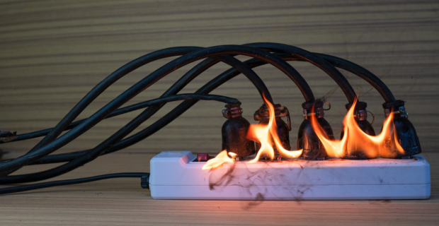 Image montrant une multiprise surchargée qui prend feu en raison d’une mauvaise utilisation et d’un manque de sécurité électrique.